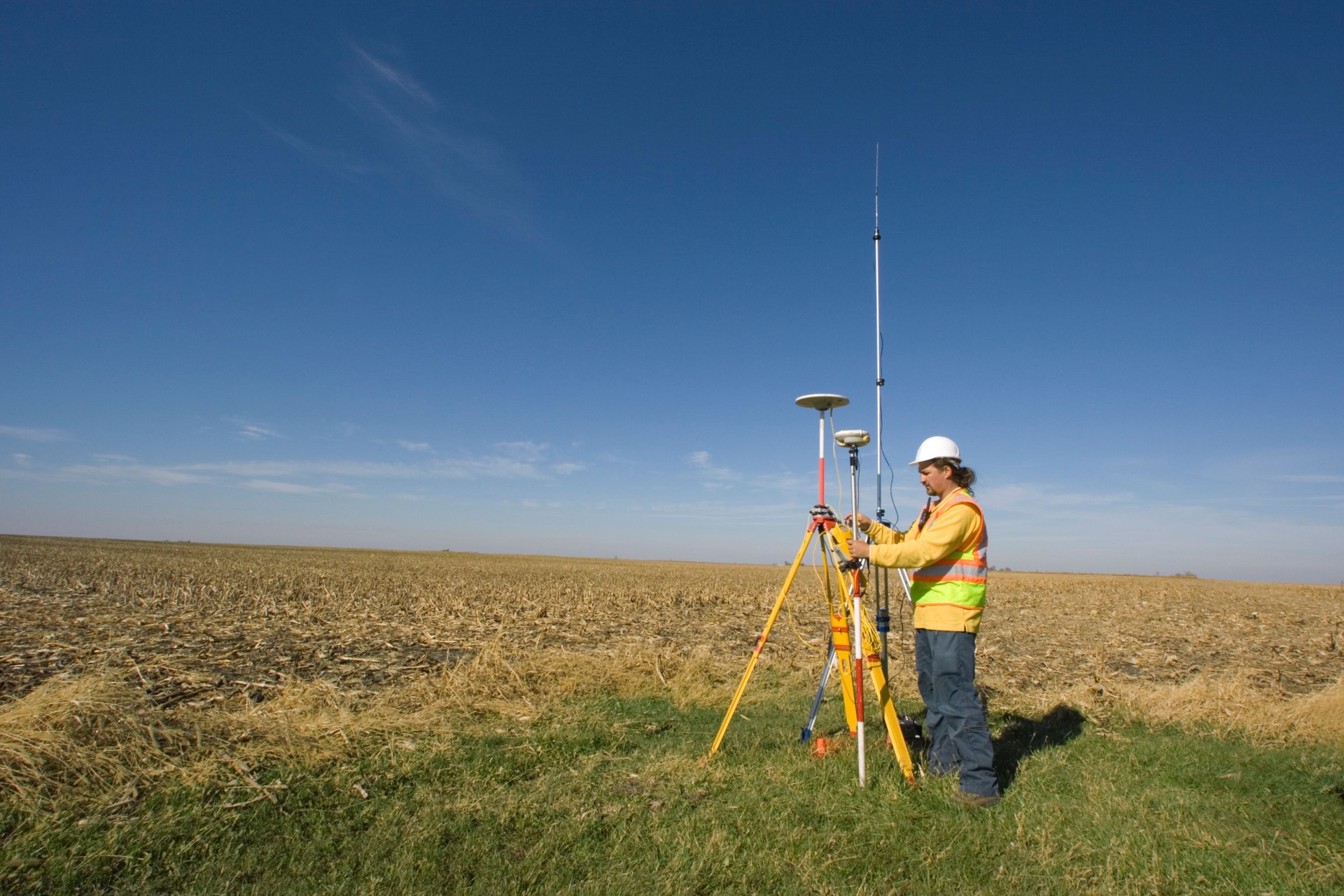 A land surveyor stood in a field taking readings with GPS